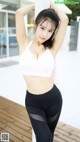 A woman in a white top and black leggings posing for a picture.