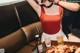 A woman in a red top sitting at a table with a plate of food.