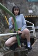 A woman in a school uniform is sitting on a railing.