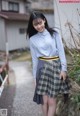 A woman in a blue shirt and plaid skirt posing for a picture.