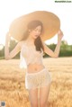 A woman in a straw hat standing in a field.