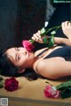 A woman laying on a table with a rose in her mouth.