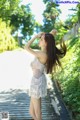 A woman in a white dress standing on a wooden walkway.