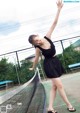 A woman in a black dress standing on a tennis court.