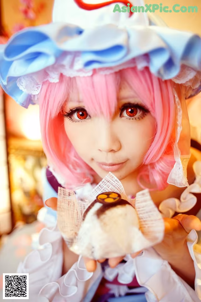 A woman with pink hair holding a piece of cake.