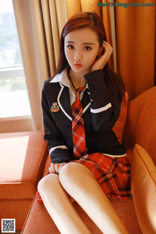 A woman in a school uniform sitting on a couch.