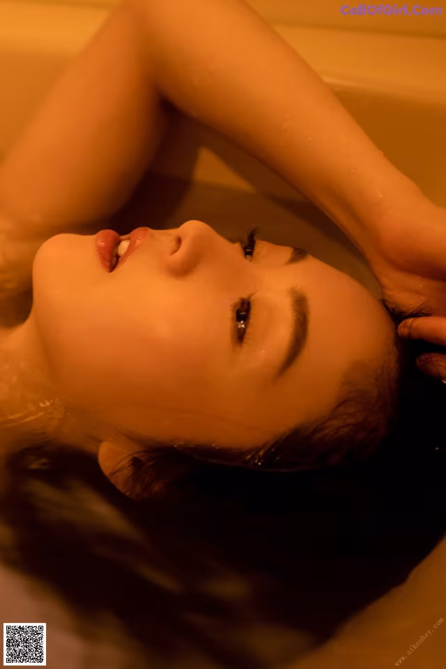A woman laying in a bathtub with her head in the water.