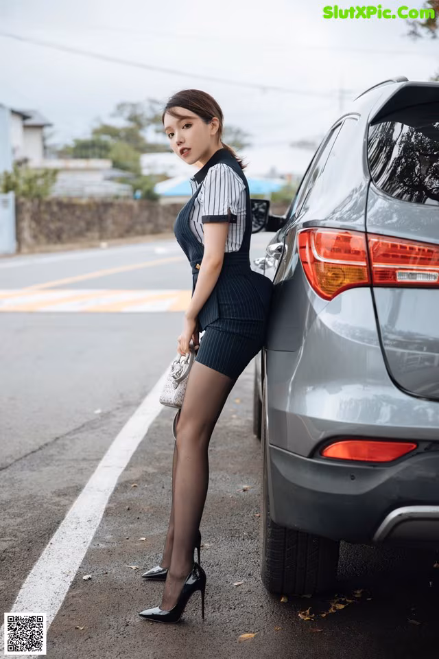 A woman standing next to a car in a parking lot.