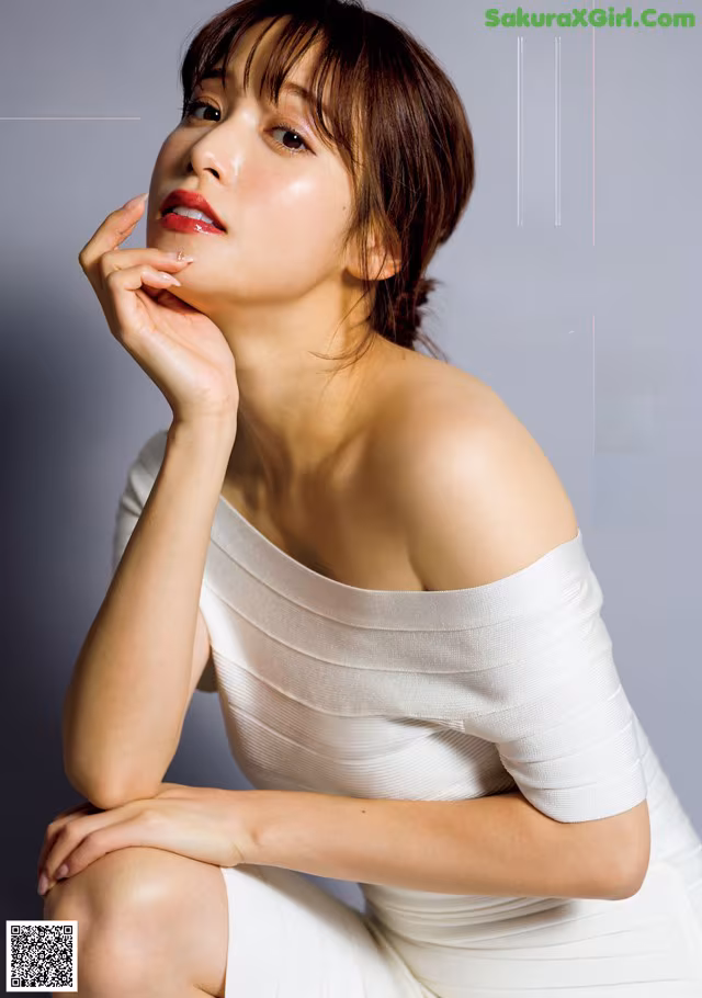 A woman in a white dress sitting on the ground.