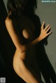 A nude woman standing in front of a wall.