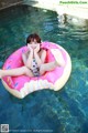 A woman sitting on an inflatable donut floating in a pool.