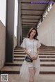 a woman in a white dress standing on some steps