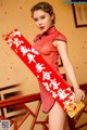 A woman in a red cheongsam holding a red envelope.