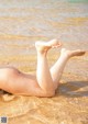 A woman laying on the beach with her legs in the water.