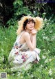 A woman in a straw hat sitting in a field of flowers.