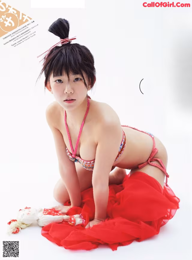 A woman in a red bikini sitting on the ground.