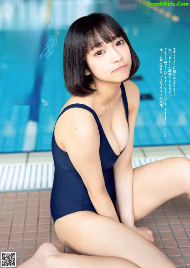 A woman in a blue bathing suit sitting by a swimming pool.
