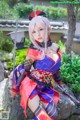 A woman in a kimono sitting on a rock with a sword.