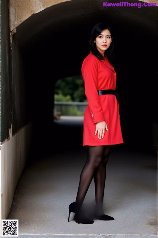 A woman in a red coat is standing in a tunnel.