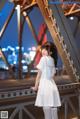 A woman in a white dress standing on a bridge.