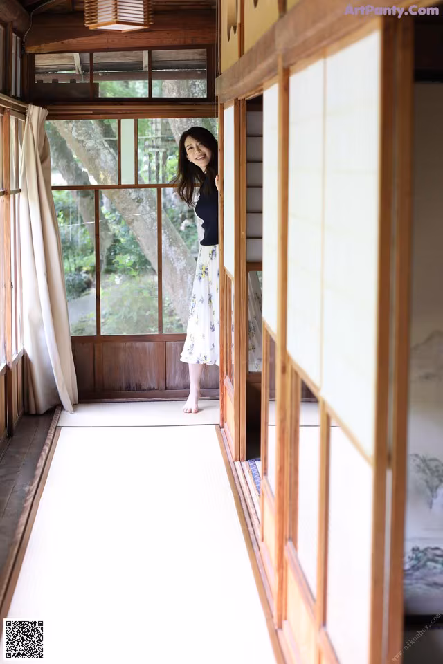 A woman standing in a room with a tatami mat.