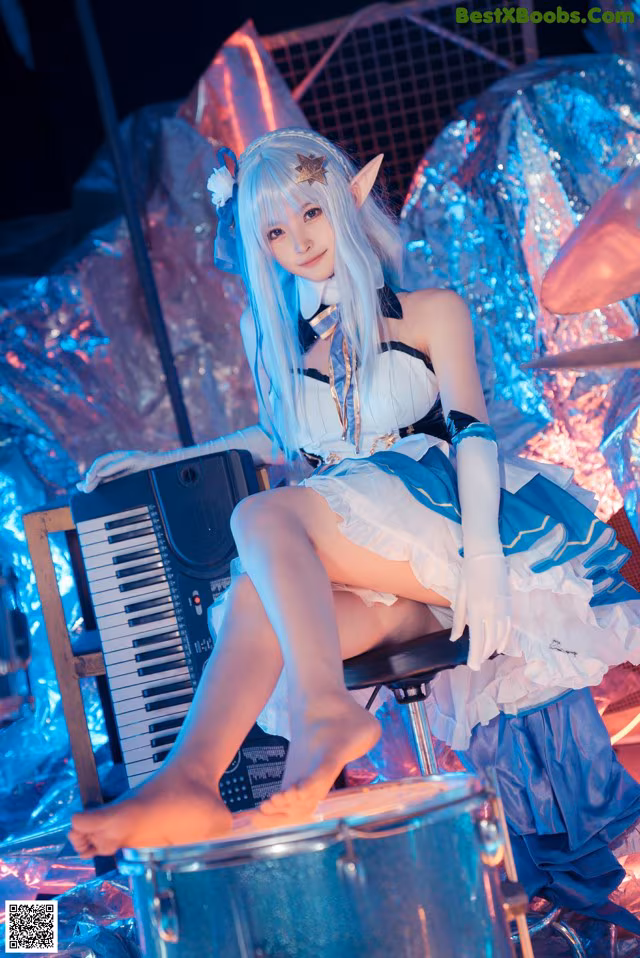 A woman sitting on top of a drum set next to a keyboard.