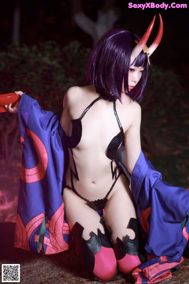 A woman in a purple and black outfit sitting on the ground.