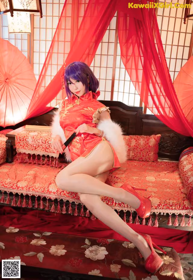 A woman in a red dress sitting on a red couch.