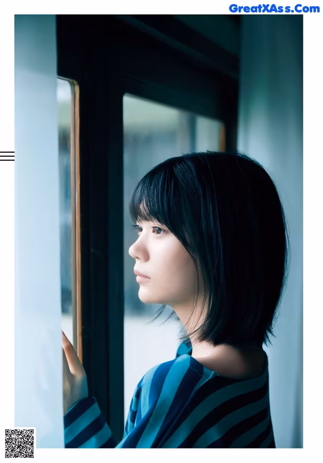 A woman looking out of a window with her hand on the window sill.